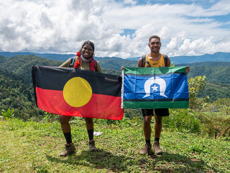 Two Y WA Kokoda participants holding the Aboriginal and Torres Strait Islander flags on a mountain summit.