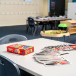 A Giant UNO card game box and spread of oversized cards on a table in a children's after-school care room
