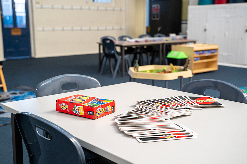 A Giant UNO card game box and spread of oversized cards on a table in a children's after-school care room