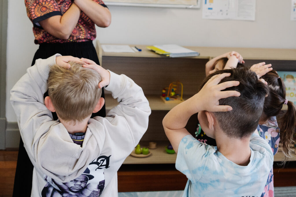 Two children playing simon says with an educator at their early learning centre.