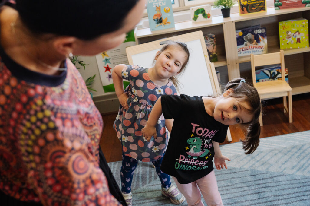 Two children engaging with an educator during mat time at their early learning centre.