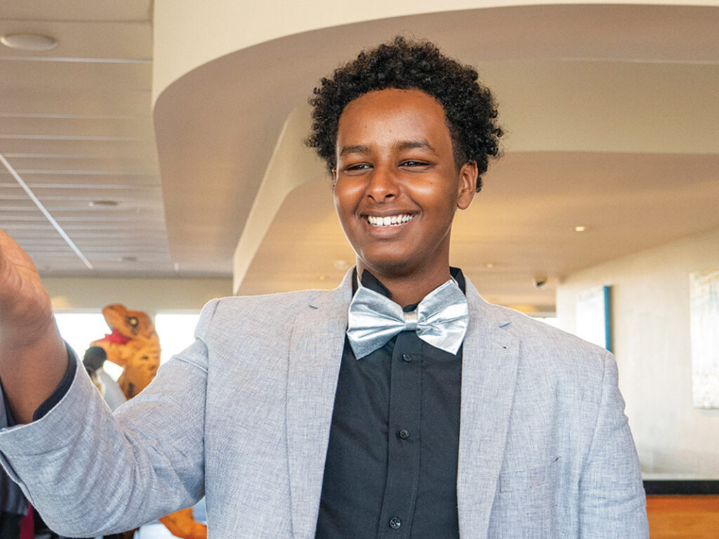 A smiling young student dressed in a grey blazer and silver bow tie at the Y School Dinner Dance