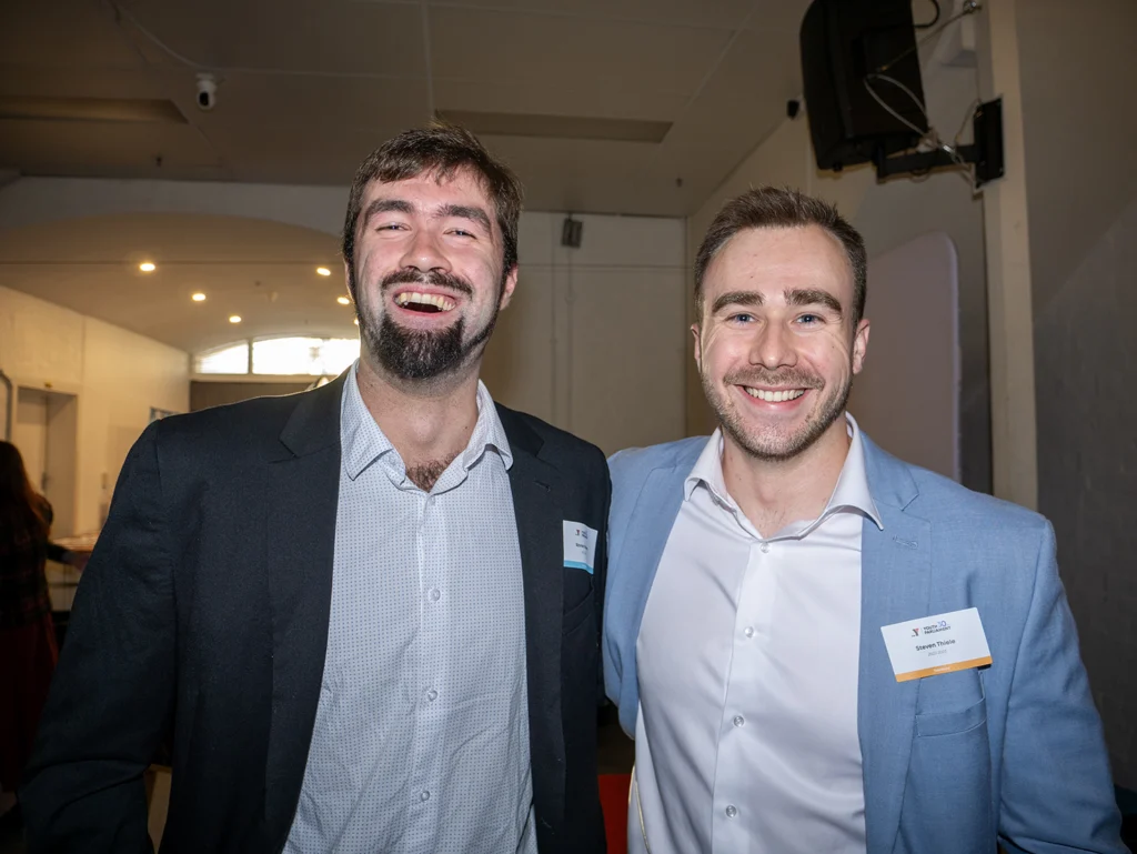 Two young men who are part of the youth parliament alumni smiling in front of camera