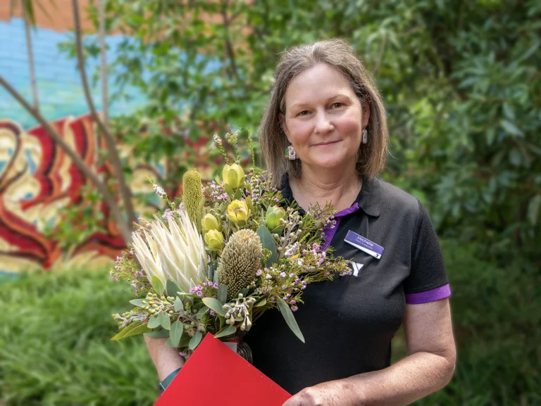 OSHC Supervisor Michelle Crossley pictured smiling and holding flowers
