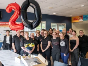 Staff from serpentine jarrahdale rec centre standing together behind a '20' balloon and cake to celebrate Kate Kings 20 years with the Y WA